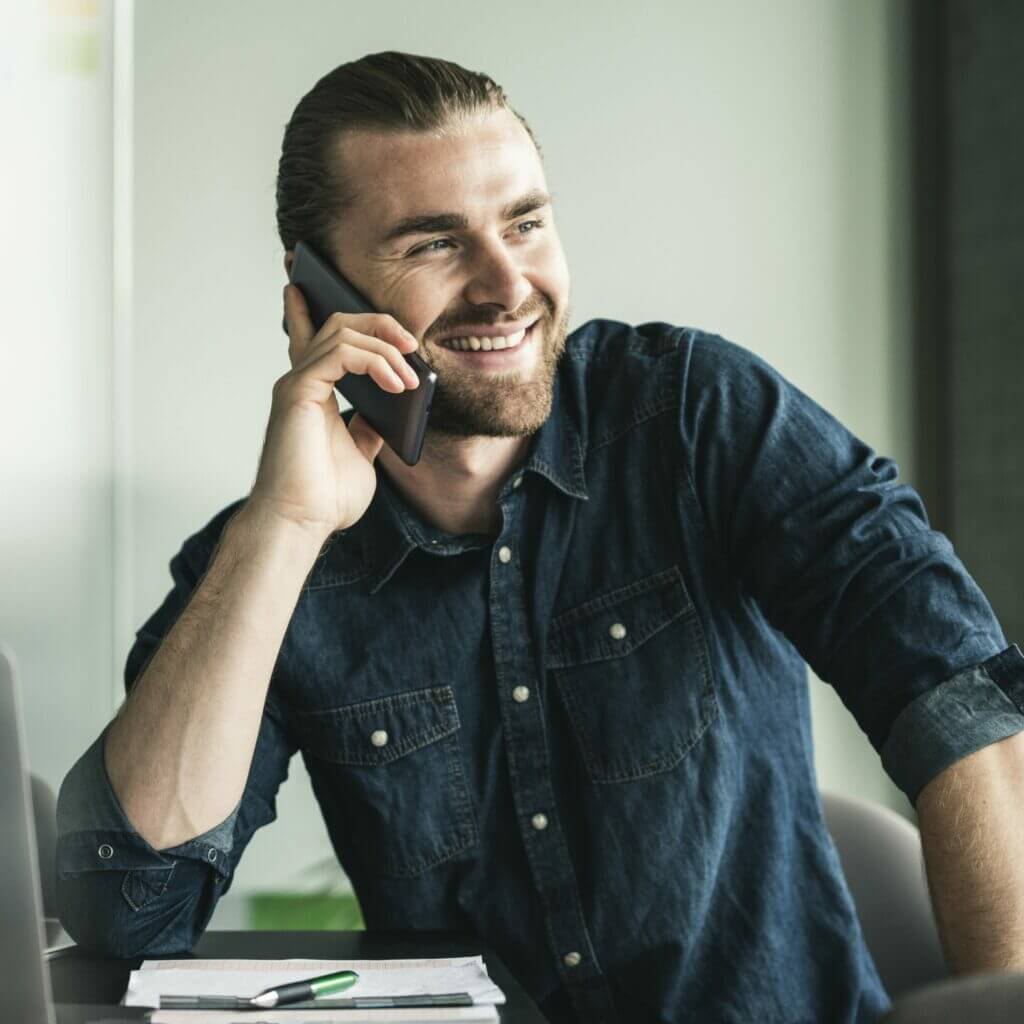 smiling young businessman on cell phone in office 2022 12 16 22 28 35 utc min (1)